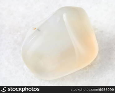 macro shooting of natural mineral rock specimen - polished white Agate gemstone on white marble background from India