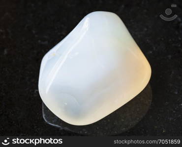 macro shooting of natural mineral rock specimen - polished white Agate gemstone on dark granite background from India