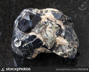 macro shooting of natural mineral rock specimen - raw black crystal of Spinel gemstone on black Diopside crystals on dark granite background from Bolshoy Gon mine, Yakutia, Russia