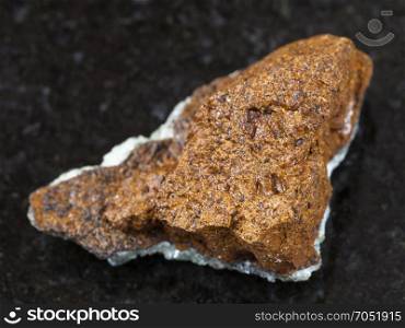 macro shooting of natural mineral rock specimen - raw bog iron ore ( limonite) stone on dark granite background from Taman Peninsula, Russia