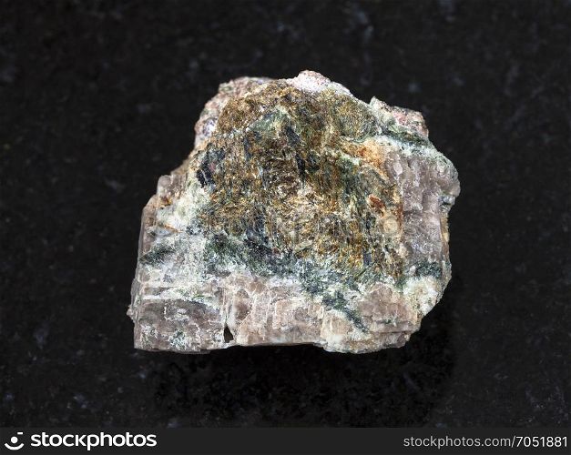 macro shooting of natural mineral rock specimen - raw Delhayelite stone on dark granite background from Yuksporr, Khibiny Mountains, Kola Peninsula, Russia