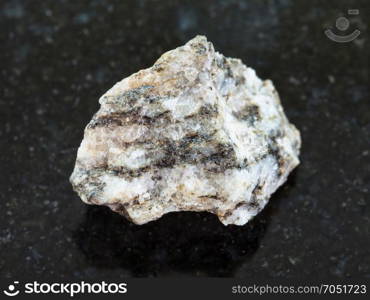 macro shooting of natural mineral rock specimen - raw Gneiss stone on dark granite background