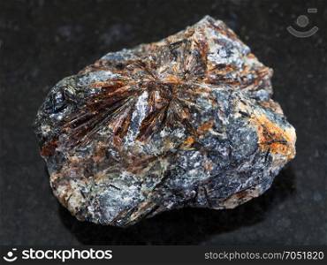 macro shooting of natural mineral rock specimen - raw lamprophyllite stone on dark granite background from Sengischorr Mount of Lovozero Massif, Kola Peninsula in Russia