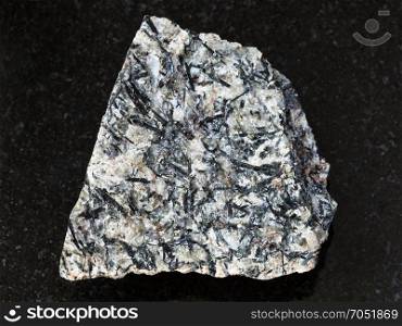 macro shooting of natural mineral rock specimen - raw lujavrite stone on dark granite background from Lovozero Massif, Kola Peninsula, Russia