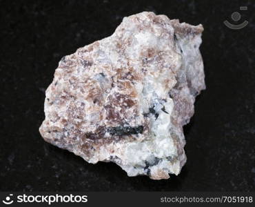 macro shooting of natural mineral rock specimen - raw Miserite stone on dark granite background from Murunskiy massiv ( Murun) , Yakutia, Russia