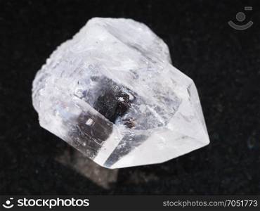 macro shooting of natural mineral rock specimen - raw rock-crystal of quartz gemstone on dark granite background