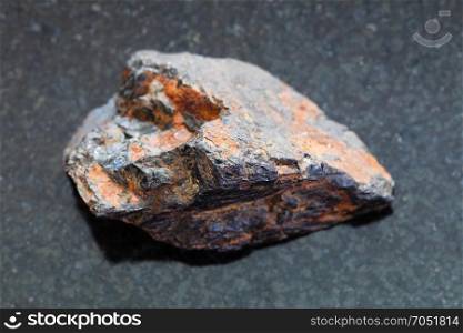 macro shooting of natural mineral rock specimen - raw Wolframite stone (tungsten ore) on dark granite background from Zabaykalsky Krai of Russia