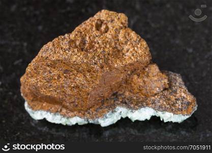 macro shooting of natural mineral rock specimen - rough bog iron ore ( limonite) stone on dark granite background from Taman Peninsula, Russia