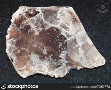 macro shooting of natural mineral rock specimen - rough brown mica sheet on dark granite background