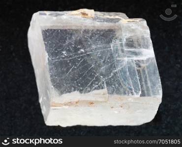 macro shooting of natural mineral rock specimen - rough crystal of Iceland spar gemstone on dark granite background from Krutoye, Evenkia in Krasnoyarsk region, Russia