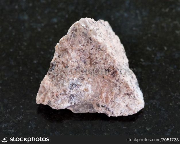 macro shooting of natural mineral rock specimen - rough Granite stone on dark granite background