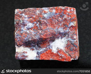 macro shooting of natural mineral rock specimen - rough Jasper stone on dark granite background from South Ural Mountains, Russia