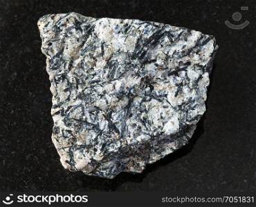 macro shooting of natural mineral rock specimen - rough lujavrite stone on dark granite background from Lovozero Massif, Kola Peninsula, Russia