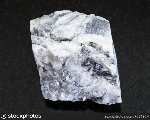 macro shooting of natural mineral rock specimen - rough magnesite stone on dark granite background from Satka, South Ural Mountains, Russia
