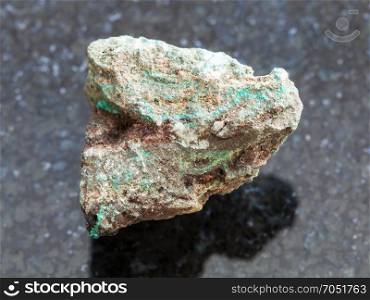 macro shooting of natural mineral rock specimen - rough Malachite (copper ore) stone on dark granite background