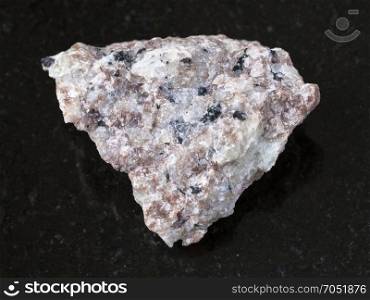 macro shooting of natural mineral rock specimen - rough Miserite stone on dark granite background from Murunskiy massiv ( Murun) , Yakutia, Russia