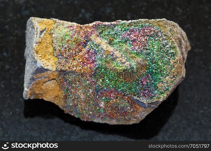 macro shooting of natural mineral rock specimen - rough rainbow pyrite stone on dark granite background from Ulyanovsk region, Russia
