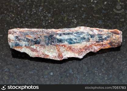 macro shooting of natural mineral rock specimen - rough Schist stone with Kyanite crystal on dark granite background