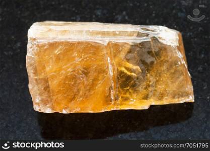 macro shooting of natural mineral rock specimen - rough tea Calcite stone on dark granite background from Mexico