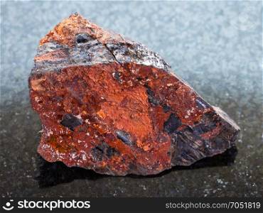 macro shooting of natural mineral rock specimen - rough Wolframite in stone on dark granite background from Zabaykalsky Krai of Russia