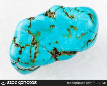 macro shooting of natural mineral rock specimen - tumbled blue howlite (turquenite) gem stone on white marble background
