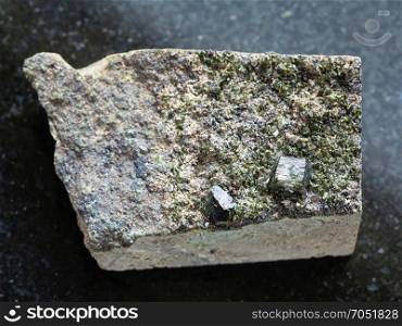 macro shooting of natural mineral stone specimen - raw green crystals of Epidote on rock on dark granite background from Irkutsk region, Russia