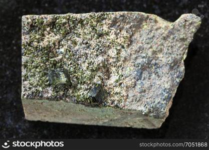 macro shooting of natural mineral stone specimen - rough green crystals of Epidote on rock on dark granite background from Irkutsk region, Russia