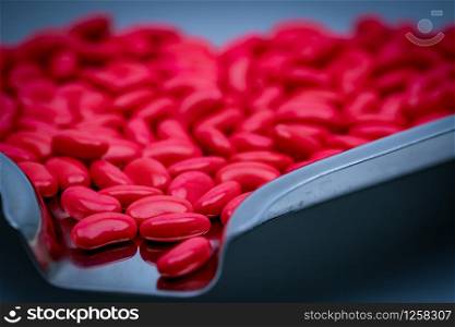 Macro shot detail of red kidney shape sugar coated tablet pills on stainless steel drug tray