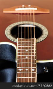 Macro shot down the fretboard of acoustic guitar with shallow depth of field