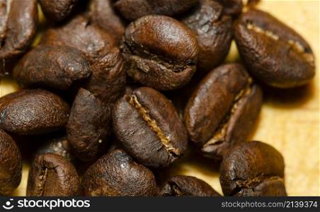 macro shot of a bunch of roasted coffee beans on a wooden table.