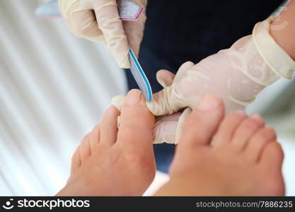 Macro shot of female feet during professional pedicure. Filing procedure at beaty spa salon