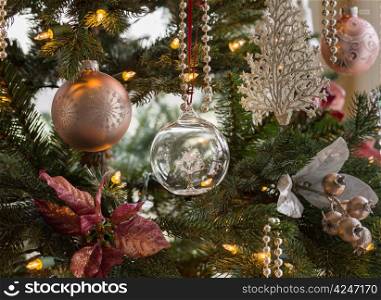 Macro shot of glass globe with tree on indoor christmas tree with decorations