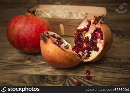 Macro shot of pomegranates and basket lying on old wooden desk