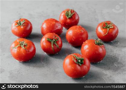 Macro shot of ripe tomatoes with drops of dew just harvested on garden. Organic food concept. Cherry tomatoes on grey background