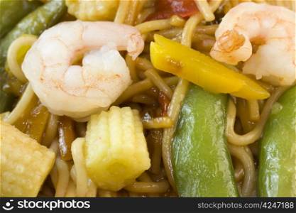 macro view of shrimp stir fry noodles with snap peas, and baby corn