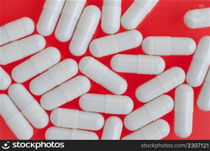Macro view of white pills on red background.