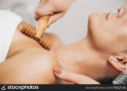 Maderotherapy Anti-Aging Massage Treatment of Woman&rsquo;s Decolletage and Neck with Wooden Roller. Maderotherapy Anti-Aging Treatment of Woman&rsquo;s Neck and Torso with Wooden Roller