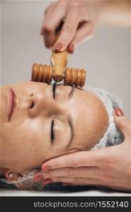 Maderotherapy Face Massage. Massaging Woman&rsquo;s Face with Wooden Double Roller Massager