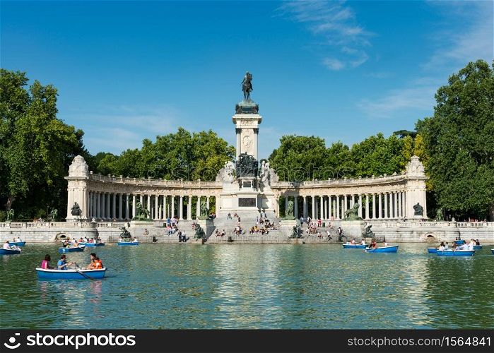 Madrid, Spain - May 30, 2015: Tourists and locals enjoy the Summer heat rowing in the main pond and resting under the monument to Alfonso XII at the Retiro Park (Parque del Buen Retiro) in Madrid, Spain.