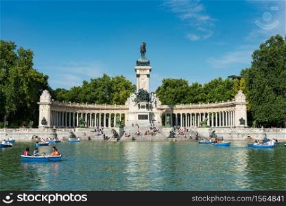 Madrid, Spain - May 30, 2015: Tourists and locals enjoy the Summer heat rowing in the main pond and resting under the monument to Alfonso XII at the Retiro Park (Parque del Buen Retiro) in Madrid, Spain.