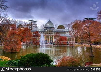 Madrid, Spain, November 30, 2019: Crystal Palace in Retiro Park in Madrid. Autumn colorful view with people, trees, plants and environment.