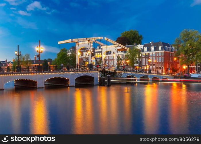 Magere Brug, Skinny bridge, with night lighting over the river Amstel in the city centre of Amsterdam, Holland, Netherlands