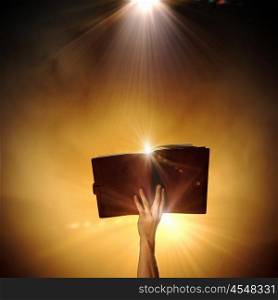 Magic book. Human hand holding magic book with magic lights