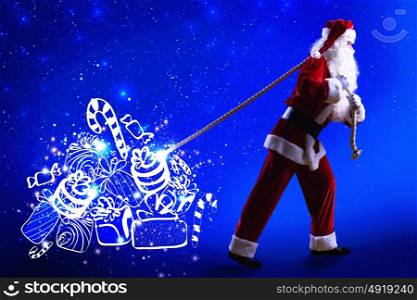 Magic Christmas eve. Santa Clause and Christmas gifts against blue background