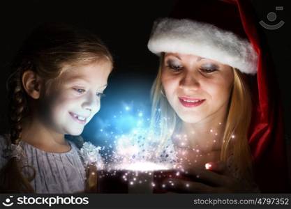 Magic Christmas. Happy mother and daughter opening Christmas gift
