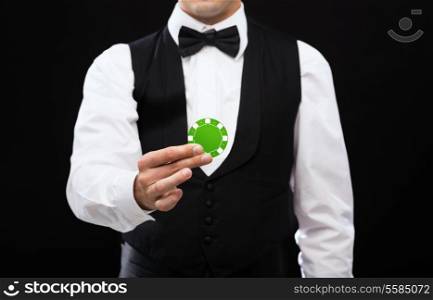 magic, performance, circus, casino and show concept - casino dealer holding green poker chip