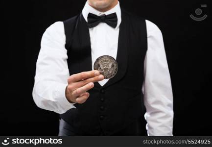 magic, performance, circus, casino and show concept - casino dealer holding half dollar coin
