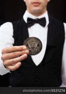 magic, performance, circus, casino and show concept - casino dealer holding half dollar coin
