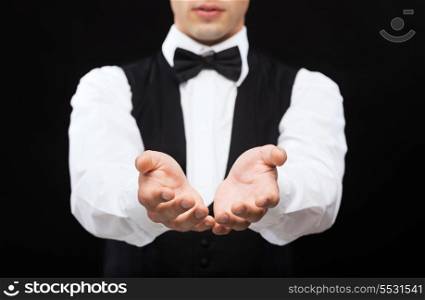 magic, performance, circus, casino and show concept - casino dealer holding something on palms of his hands