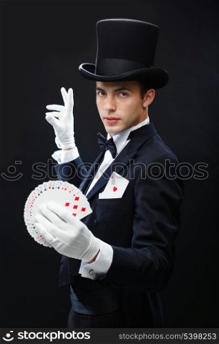 magic, performance, circus, gambling, casino, poker, show concept - magician in top hat showing trick with playing cards